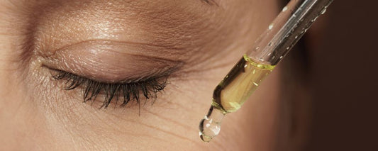 A woman applying golden facial oil to her glowing skin